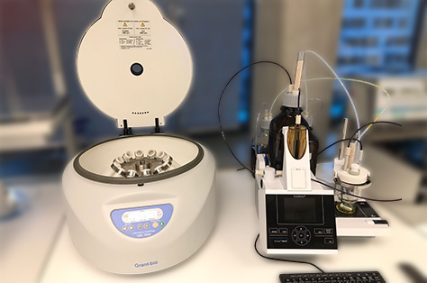 Laboratory centrifuge and automated titration equipment setup on a lab bench with blurred background.