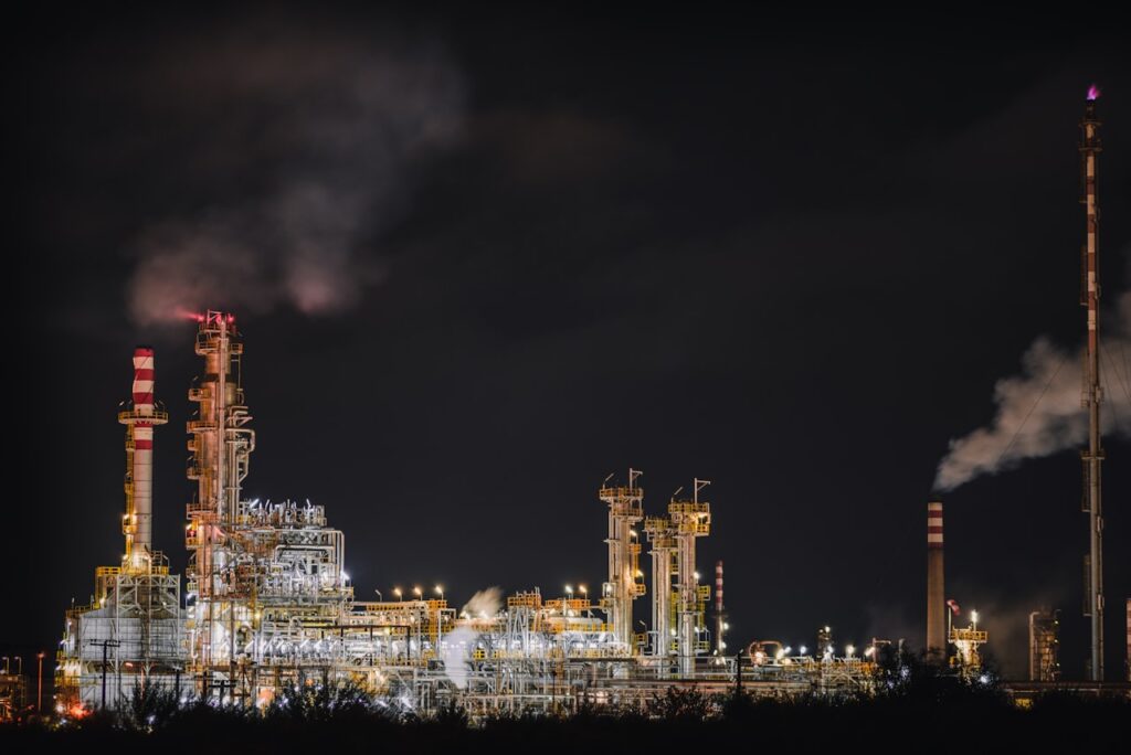 Industrial oil and gas refinery at night where corrosion inhibitor programmes protect steel infrastructure