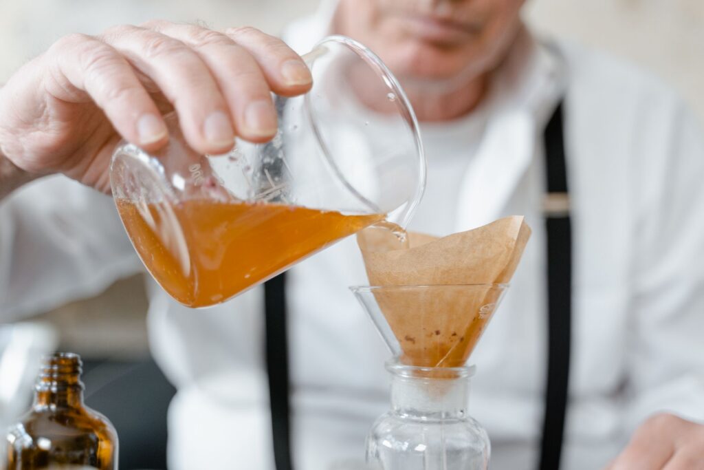 Amber liquid poured through a paper filter funnel in a laboratory