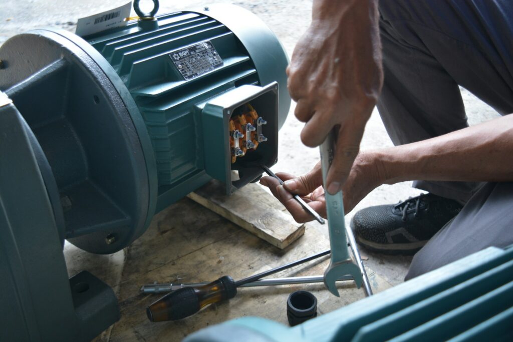 Technician working on an electric motor with a wrench during equipment maintenance